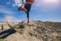 Une coureuse en legging noir et baskets roses accélérant sur une colline aride, soulignant l'importance des leggings pour le soutien musculaire et la mobilité pendant la course